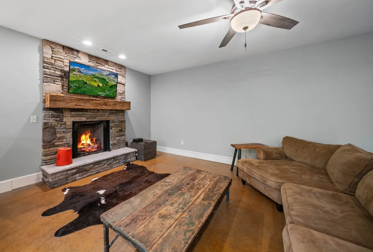 The scene centers on a welcoming seating area with a sofa, coffee table, fireplace, and large TV. The setup is perfect for movie nights, board games, and relaxing by the fire with loved ones, creating a sense of togetherness.