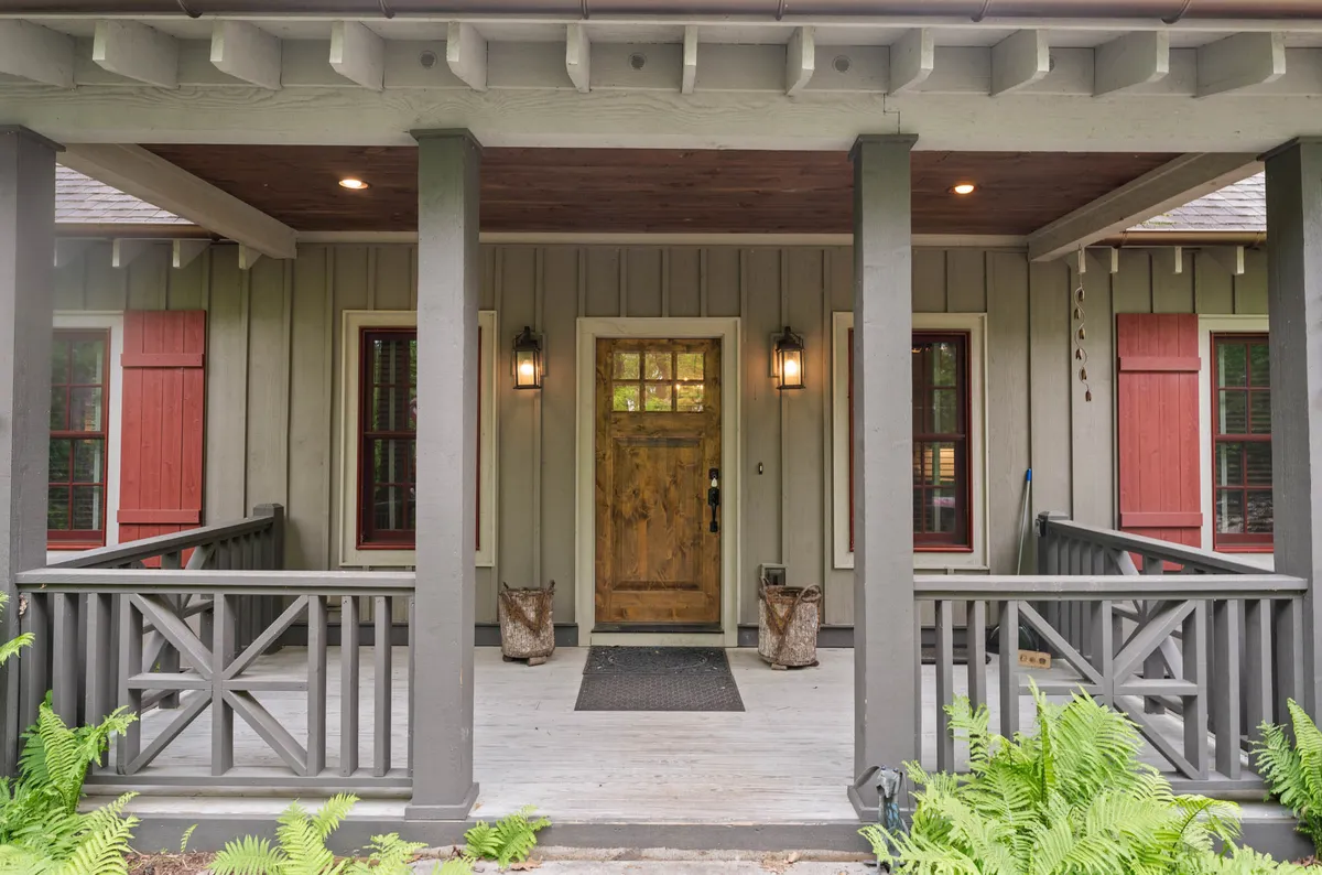 This image focuses on the welcoming wooden front door accented by lantern lights, ferns, and railings, creating an inviting entryway that hints at a warm, pet-friendly retreat after a day exploring the outdoors.