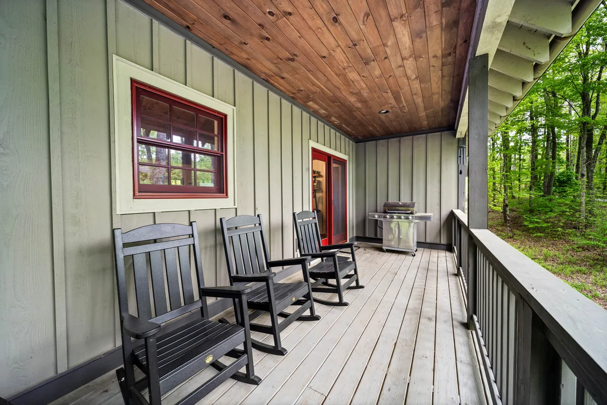 A deck with classic rocking chairs positioned near a grill, overlooking peaceful greenery. The setup exudes a laid-back vibe, encouraging morning coffee or relaxing evenings while taking in the fresh mountain air.