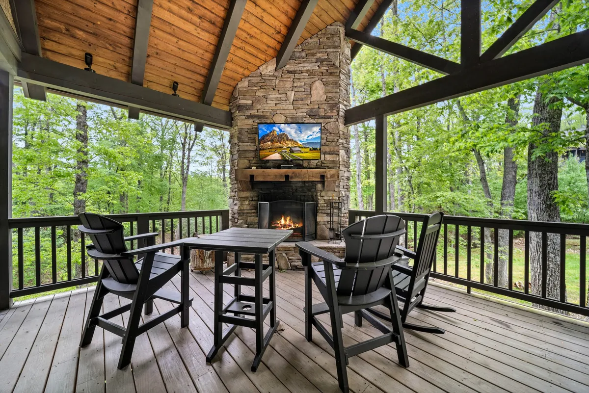 A cozy outdoor living area with a stone fireplace, ample seating, and a wood-paneled ceiling. Set up for gatherings, it blends comfort and open-air exposure, suggesting evenings spent outdoors sharing stories or watching the stars after a day of adventure.